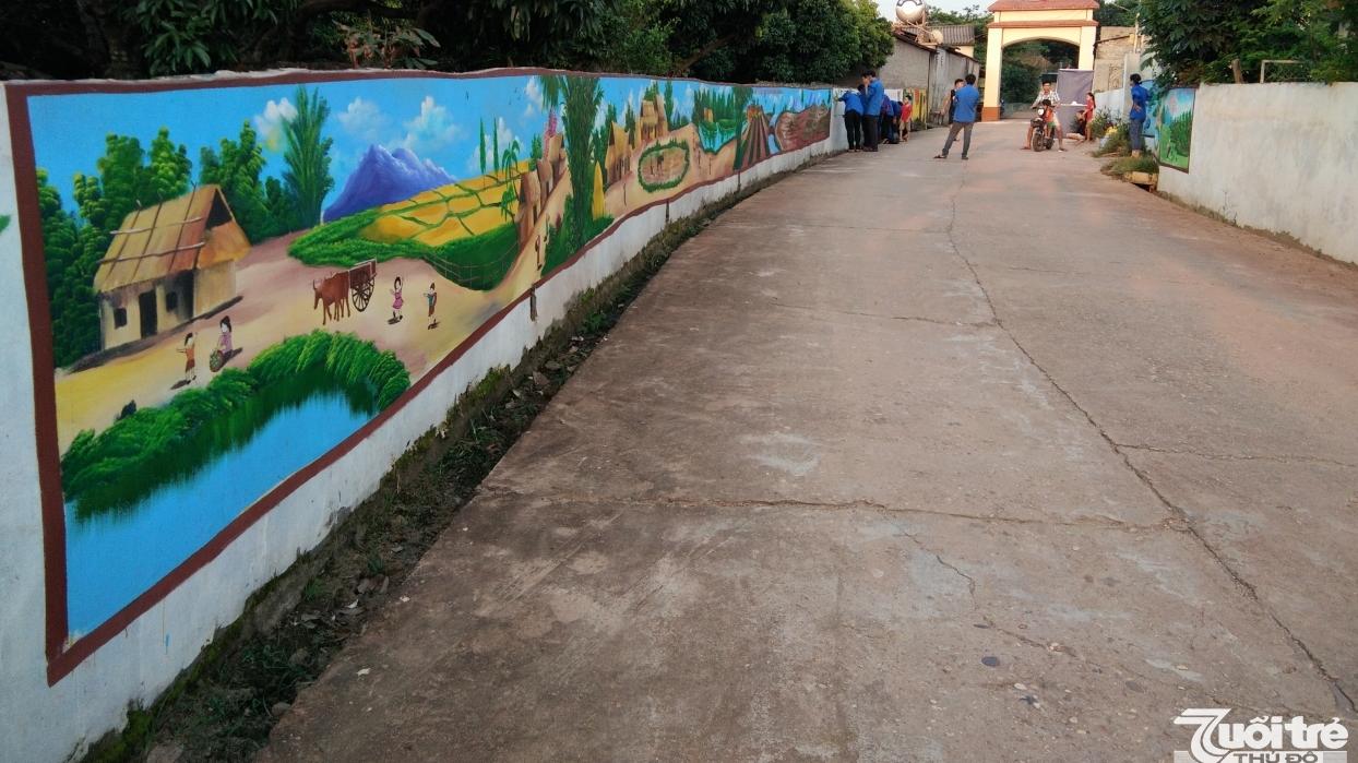 Con đường trục thôn đã được bê tông hóa, hai bên tường bao được trang trí bằng các bức bích họa sinh động về làng quê Việt Nam