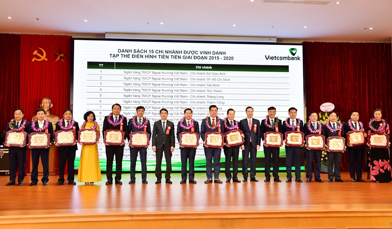 Chủ tịch HĐQT Vietcombank Nghiêm Xuân Thành (thứ 7 từ trái sang) và Tổng Giám đốc Vietcombank Phạm Quang Dũng (thứ 7 từ phải sang) trao tặng biểu trưng và hoa cho 15 chi nhánh đã có thành tích tiêu biểu, là tập thể điển hình tiên tiến giai đoạn 2015 - 2020