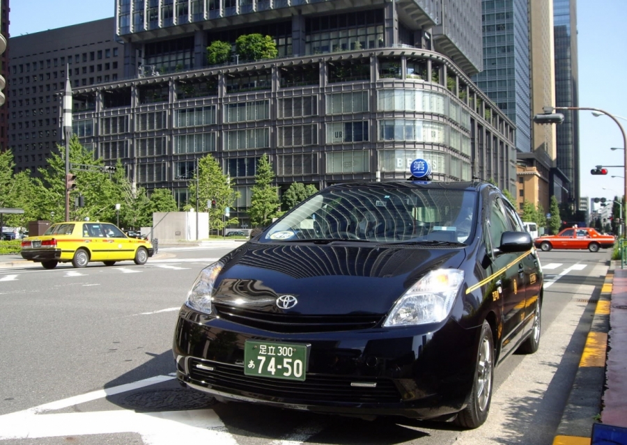 Một chiếc taxi có biển số nền xanh và chữ trắng trên đường phố Nhật Bản (Ảnh: NIKKEI)