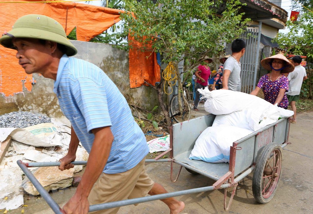 Người dân thôn Nhân Lý, xã Nam Phương Tiến đến nhận hàng cứu trợ tại các tổ trong thôn. (Ảnh: Thành Đạt/TTXVN)