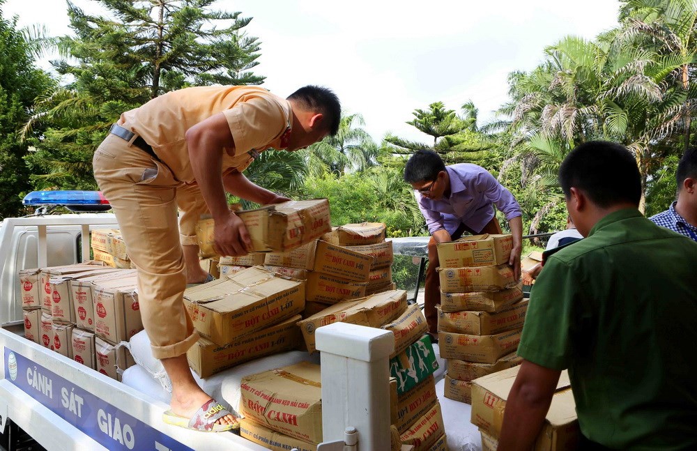 Công an xã Nam Phương Tiến chuyển hàng cứu trợ lên xe để đưa đến cho người dân các thôn. (Ảnh: Thành Đạt/TTXVN)