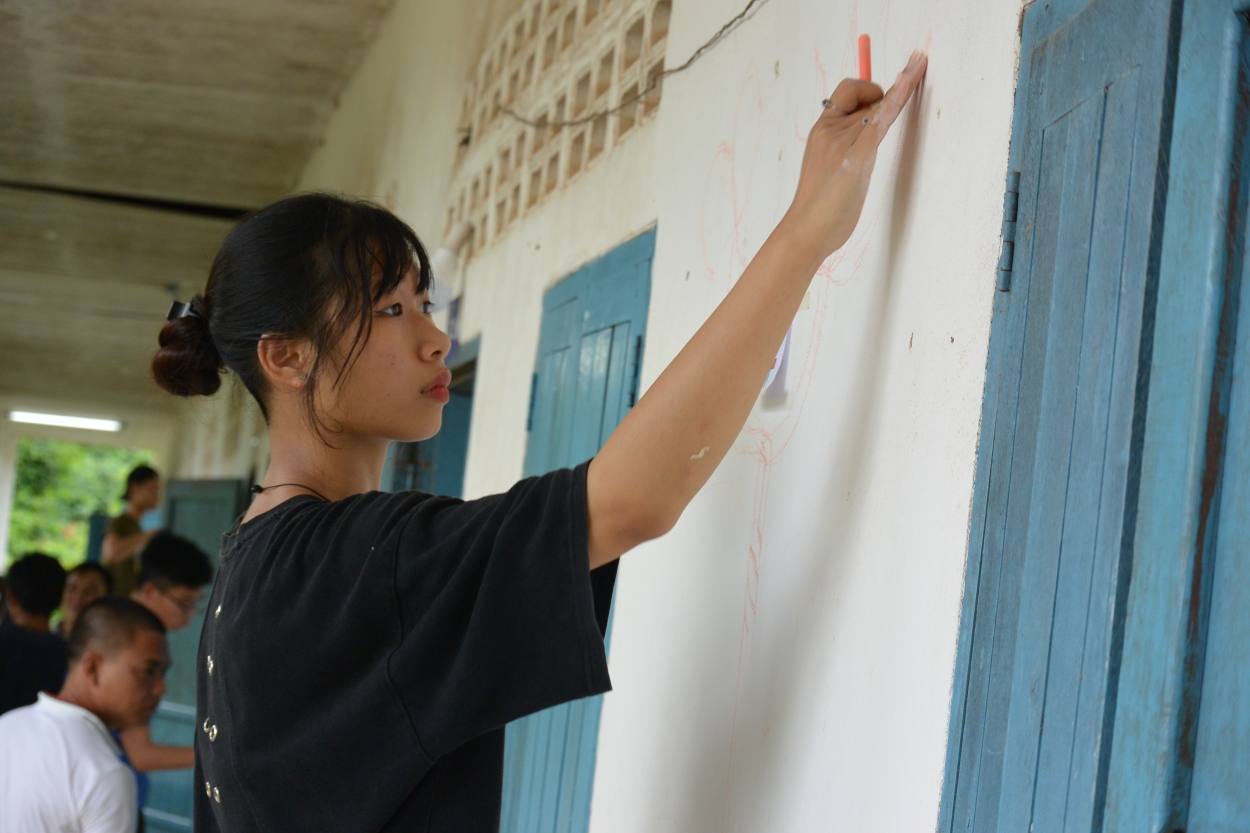 Bạn Nguyễn Thục Huyền, sinh viên trường Đại học Mỹ thuật Công nghiệp đang phác thảo các chi tiết để chuẩn bị trang trí lại trường tiểu học Napock, huyện Saythany