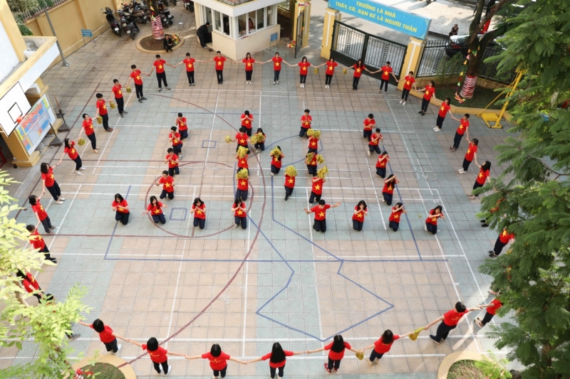 Các bạn học sinh xếp hình tên trường Trần Nhân Tông với những chữ cái đầu tiên. Hình ảnh này nổi bật hơn với chiếc áo màu cờ đỏ sao vàng của Việt Nam