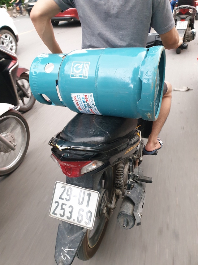 Nhiều người chở bình gas mà không có dây chằng buộc, vừa đi vừa vòng một tay ra sau để giữ bình gas