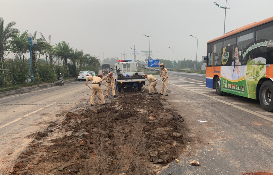 Các chiến sỹ Đội CSGT số 15 (Phòng CSGT Công an TP Hà Nội) dọn đống bùn thải bị đổ vãi trên đường Võ Nguyên Giáp