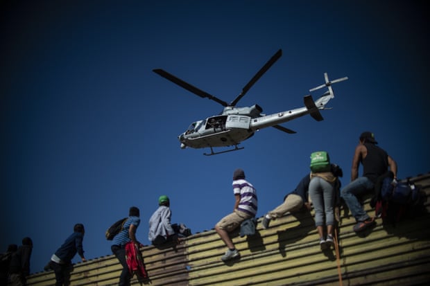 Những người di cư leo lên hàng rào áp sát biên giới Mỹ tại khu vực thành phố Tijuana. Ảnh: Getty Images
