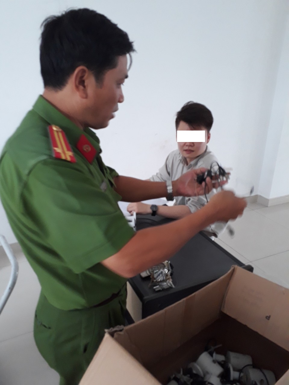 Nhân viên kỹ thuật tháo gỡ camera không phép bị cư dân tạm giữ cùng vật chứng chờ công an kiểm kê.