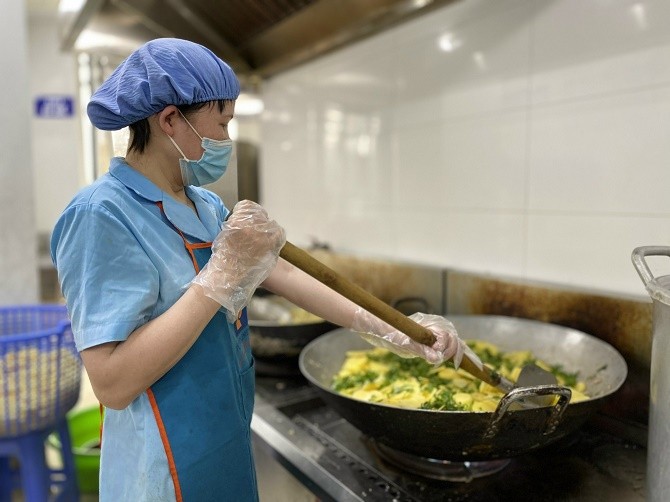 Nhân viên bếp ăn được trang bị đầy đủ bảo hộ lao động để đảm bảo VSATTP trong quá trình chế biến thức ăn cho học sinh