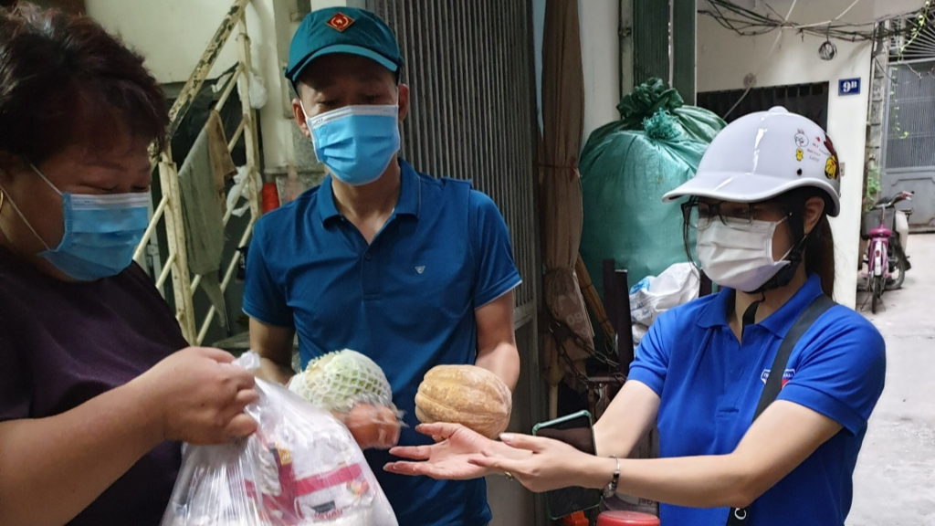 Nguyễn Thu Trang (bên phải) hỗ trợ hoạt động tặng nhu yếu phẩm đến người dân 